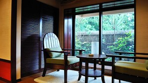 Ett rum med ett stort fönster, en stol, ett litet bord och en soffa.