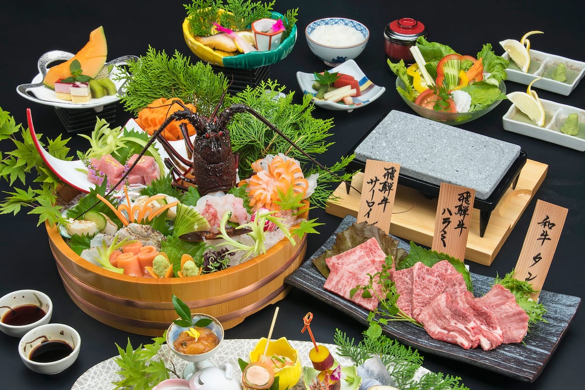 Variedad de platos de sushi y sashimi, incluyendo nigiri y sashimi, dispuestos sobre una mesa de madera con recipientes pequeños de salsa de soja y wasabi.