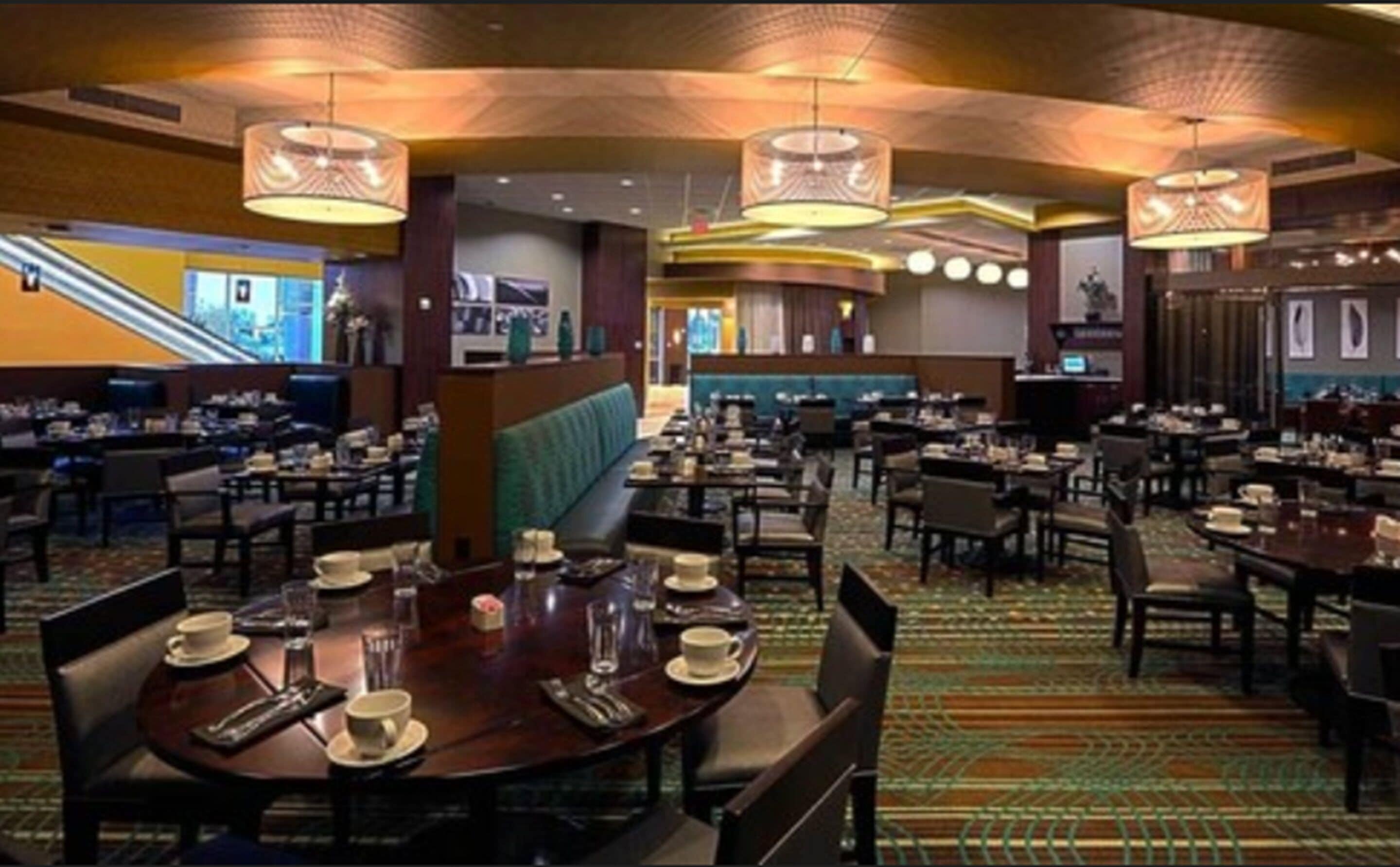 A hotel dining area with multiple tables, chairs, and a central seating area.