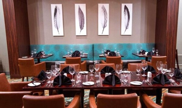 Un salón de conferencias con mesas dispuestas para comer, equipado con sillas y cristalería.