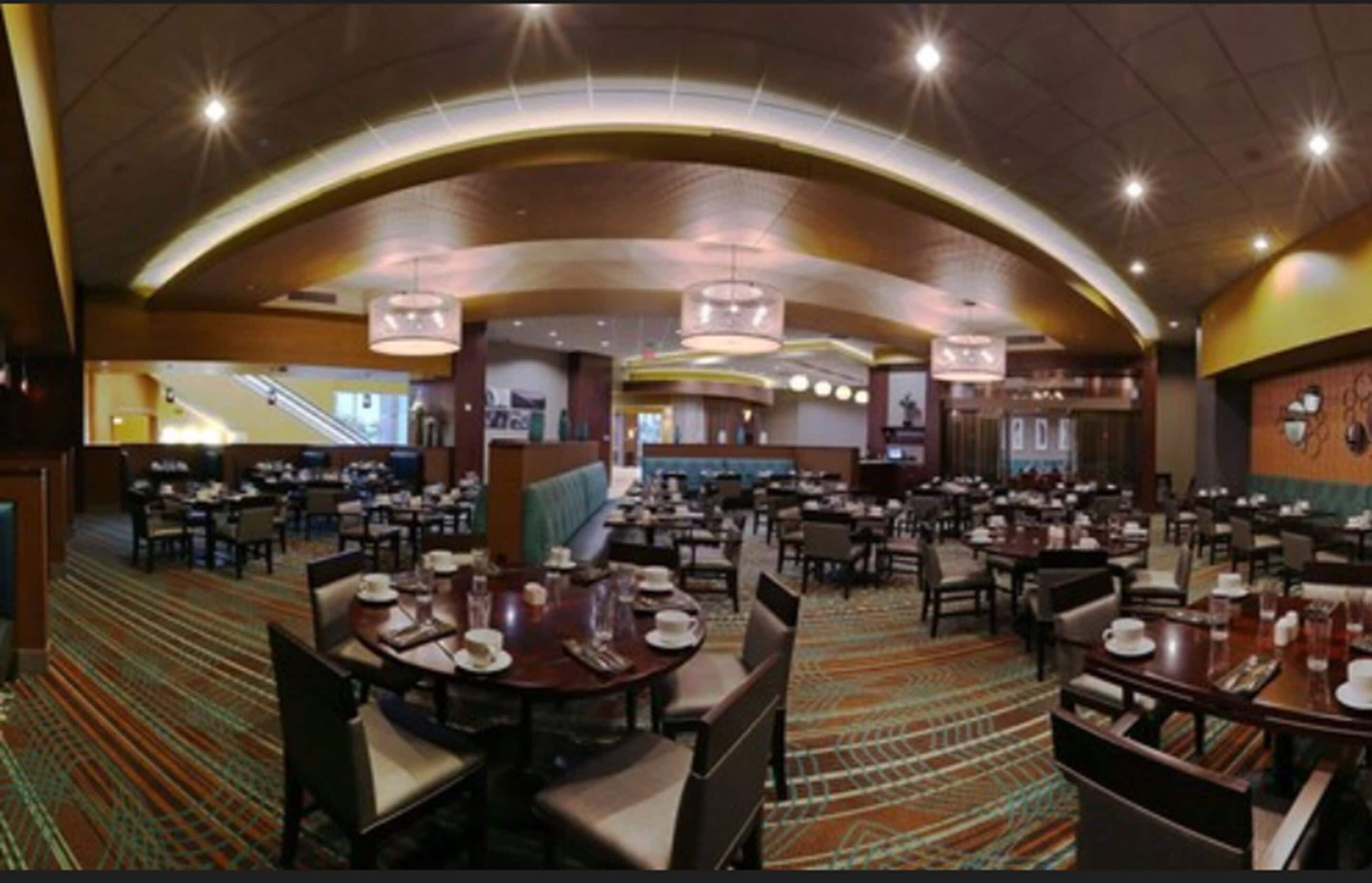 Un restaurante amplio con varias mesas y cabinas, techo curvo y piso alfombrado.