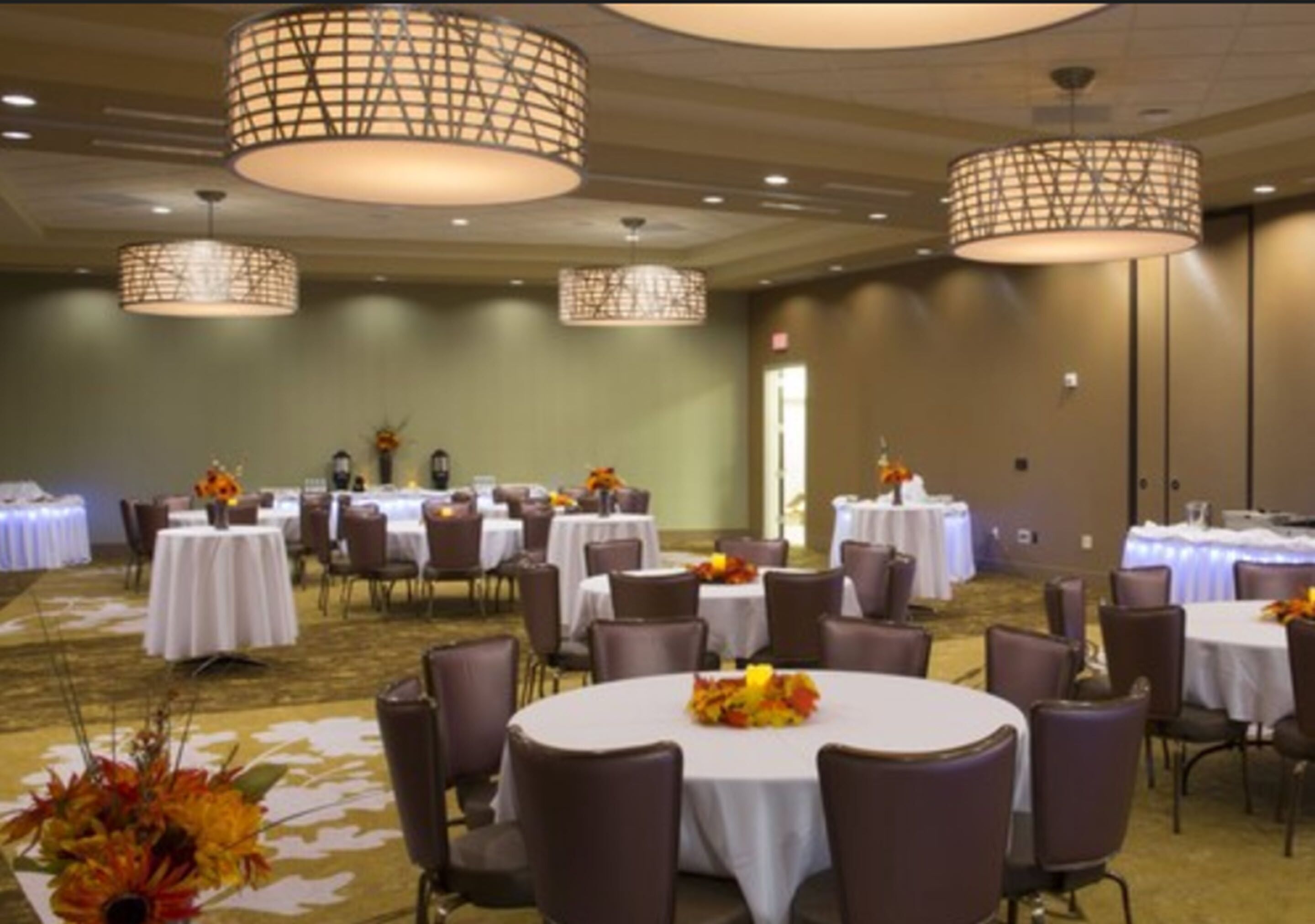 A conference room with round tables, chairs, and decorative centerpieces.