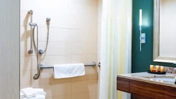 A bathroom with a shower, a towel rack, a mirror, and a vanity with a sink.