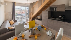 Un apartamento moderno con comedor, cocina y escalera.