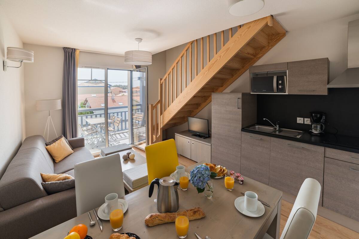 Een modern appartement met een eethoek, keuken en een trap.