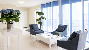 Una sala de estar moderna con dos sillones grises, una mesa de centro blanca y una planta en maceta.