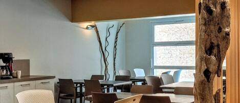 A modern dining area with a wooden table and chairs, recessed ceiling lights, and a large wooden sculpture.