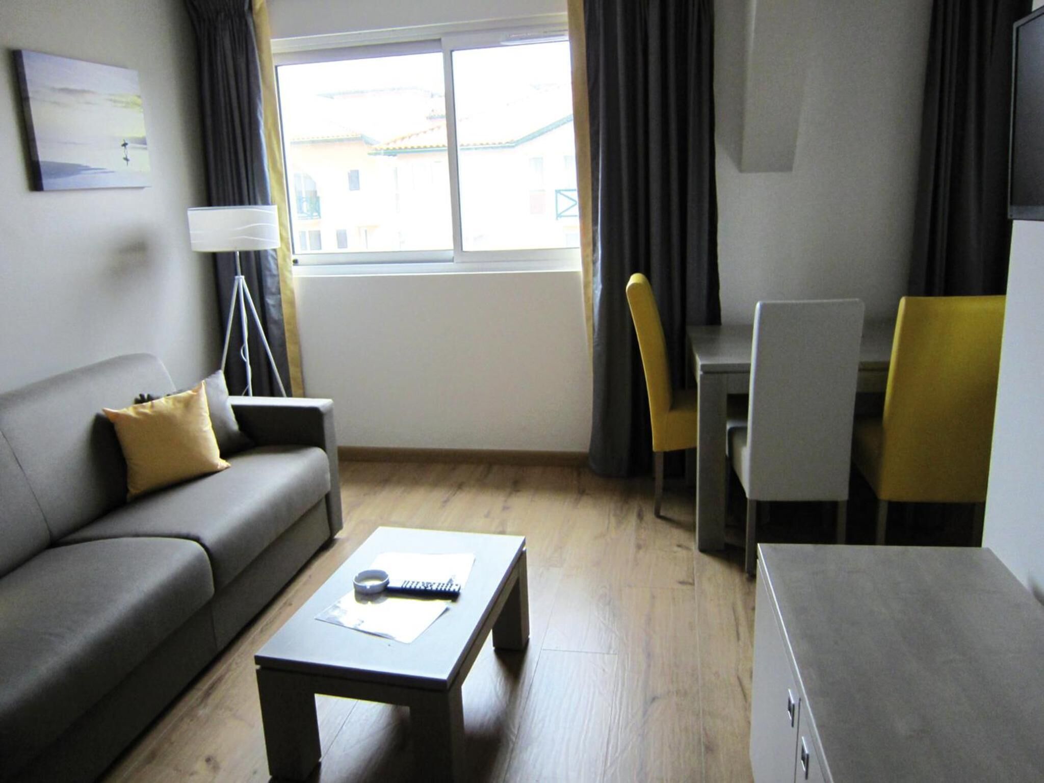 A modern living room with a sofa, coffee table, and a dining area with chairs and a table.
