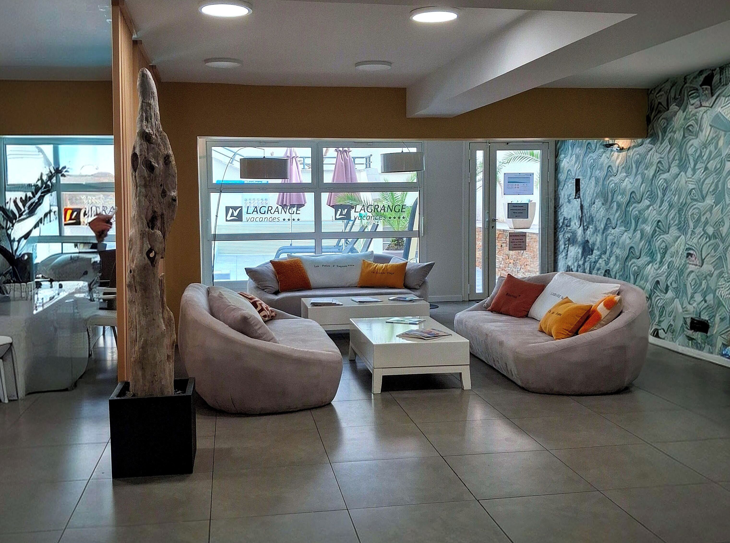 A modern living room with sofas, a coffee table, and a large wooden sculpture.