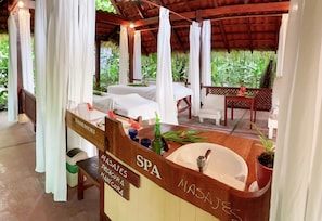 A spa area with a wooden counter, a sink, and a massage table.