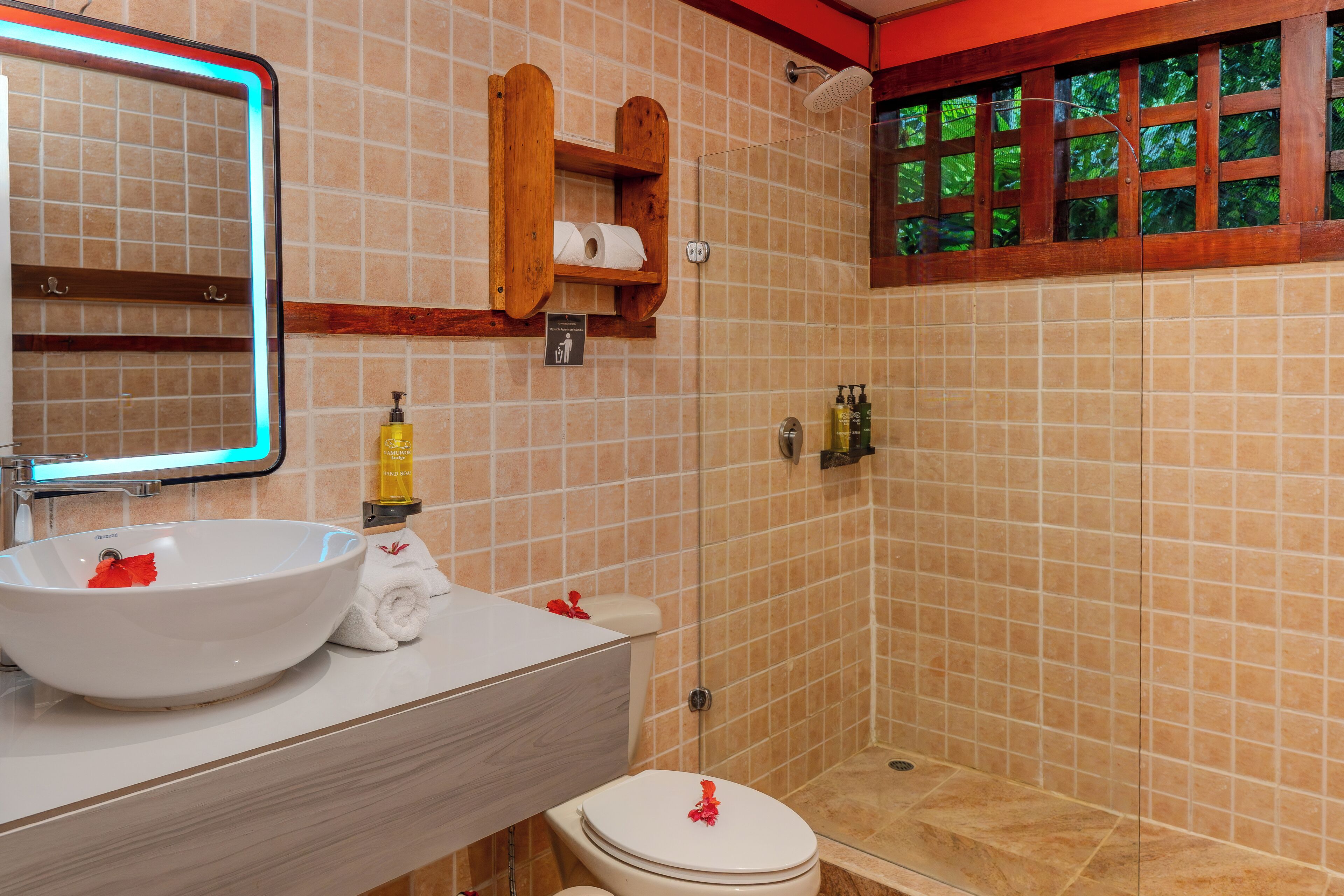 Un baño con lavamanos blanco, un espejo, inodoro y zona de ducha.