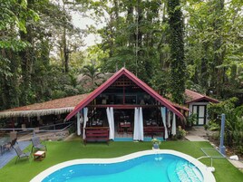 Una casa con piscina, rodeada de exuberante vegetación.