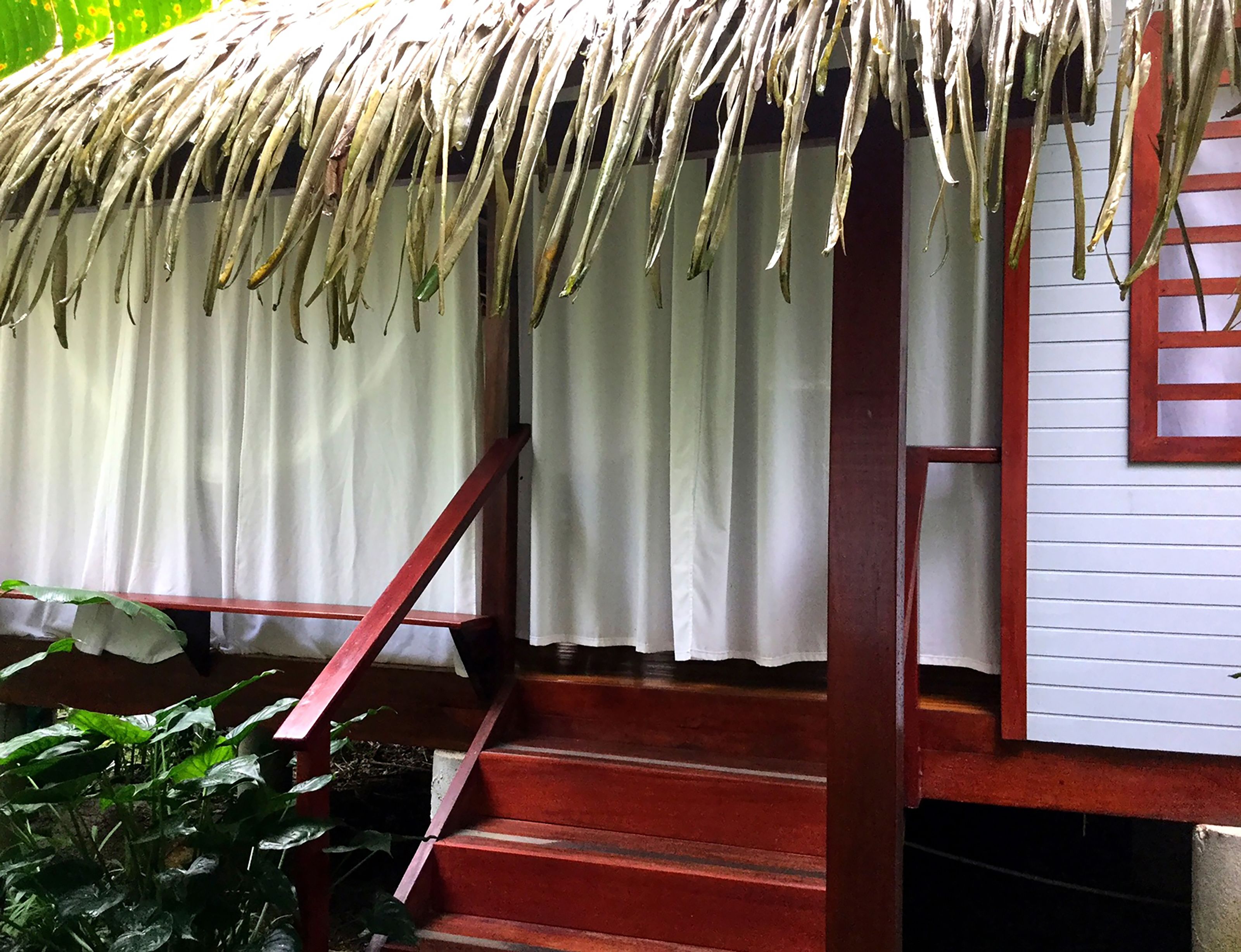 A staircase leading to a room with a thatched roof and white curtains.