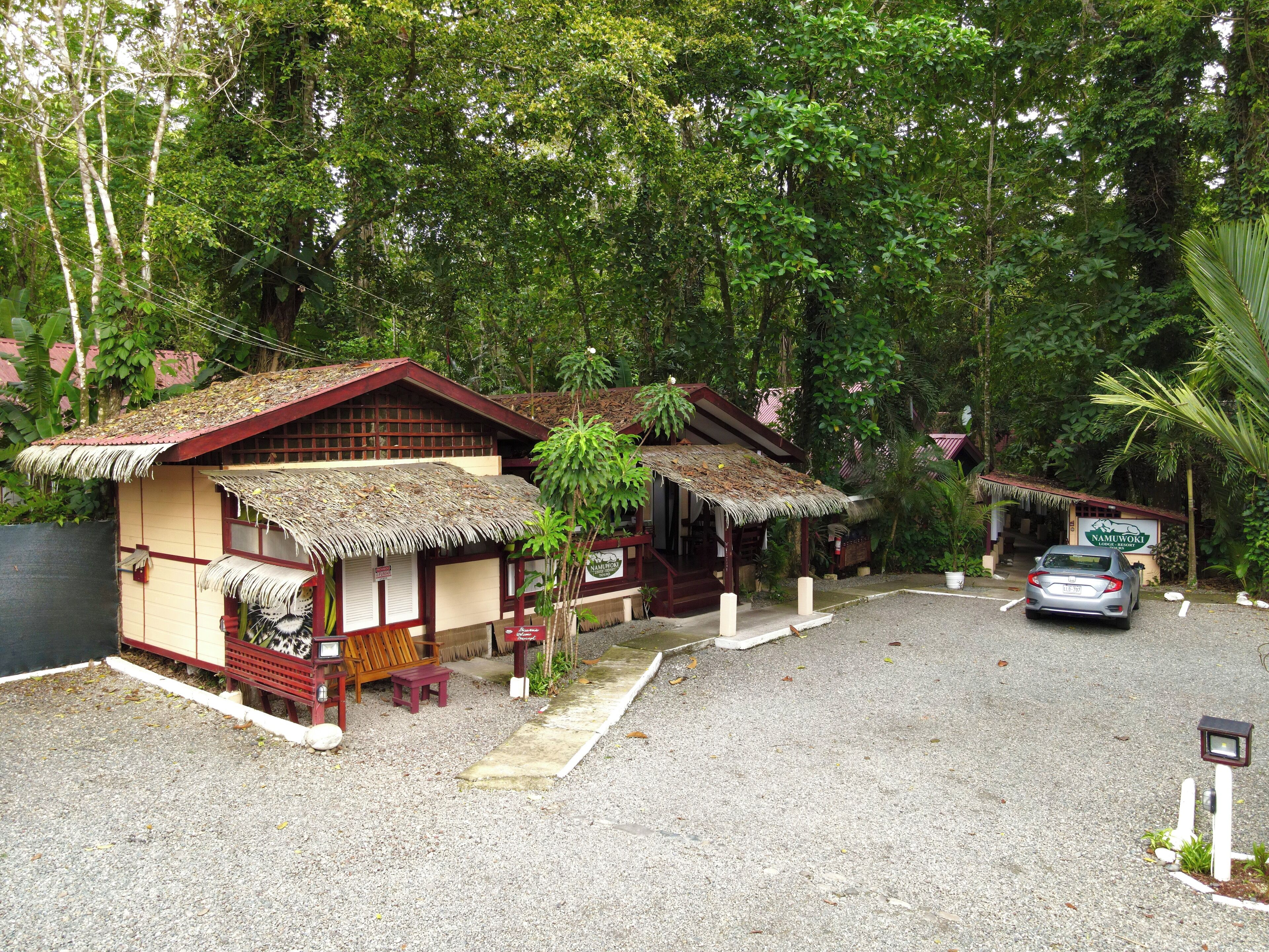 Um edifício tradicional com telhado de palha, entrada de cascalho e um carro estacionado.