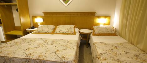 A hotel room with two beds, a wooden headboard, a nightstand with a phone, and a wall-mounted picture.