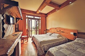 A bedroom with two beds, a wooden headboard, a television, and a window with curtains.