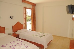 A hotel room with two beds, a television, and a window with curtains. - Ares City Hotel (Kemer)