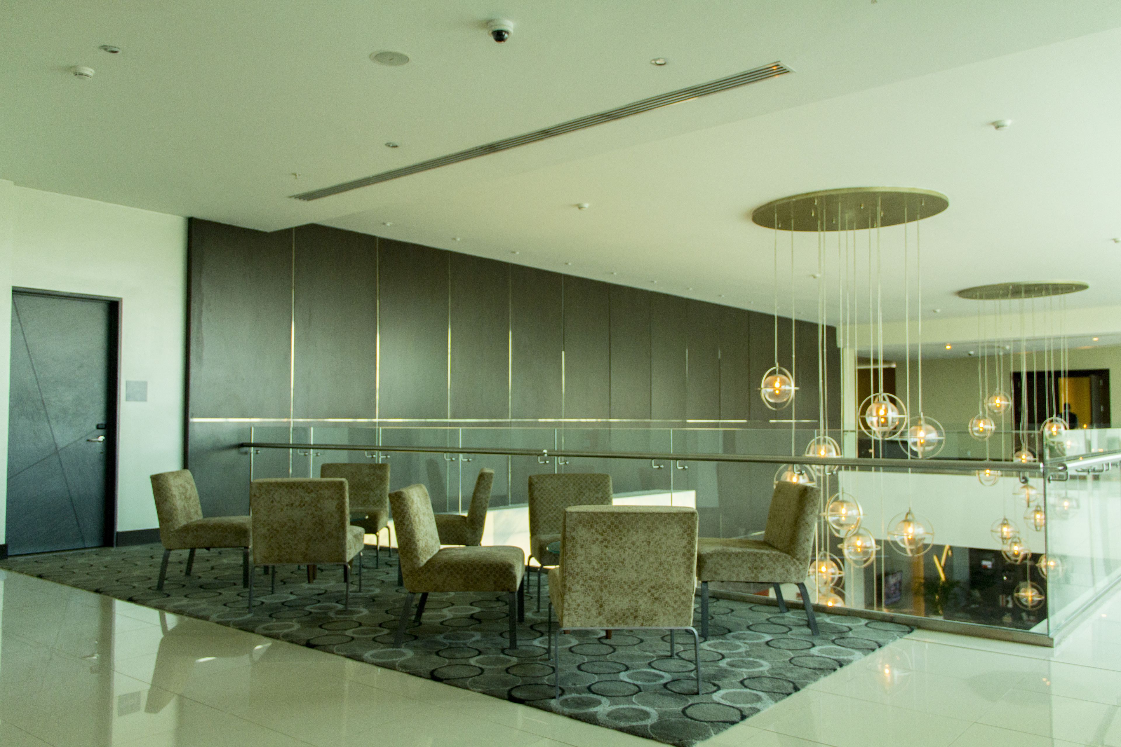 A modern lobby with a glass partition, seating area, and contemporary lighting.
