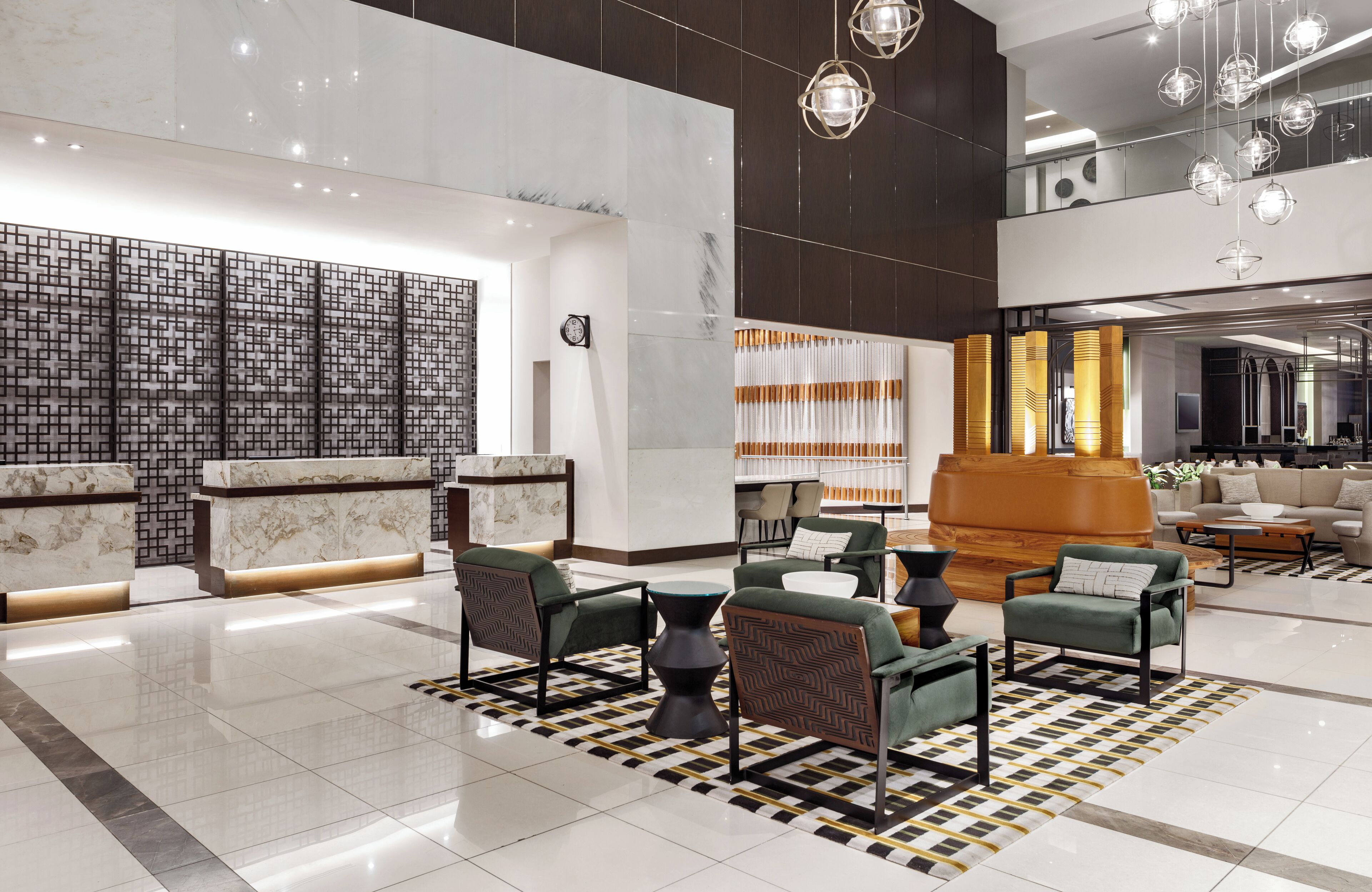 Un lobby moderno con mostrador de recepción, área de descanso y una escalera que lleva a un nivel superior.