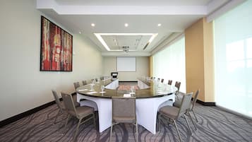 A conference room with a large oval table, chairs, a projector screen, and a large abstract painting on the wall.