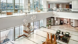 Un vestíbulo amplio con techos altos, ventanas grandes y lámparas de iluminación moderna.