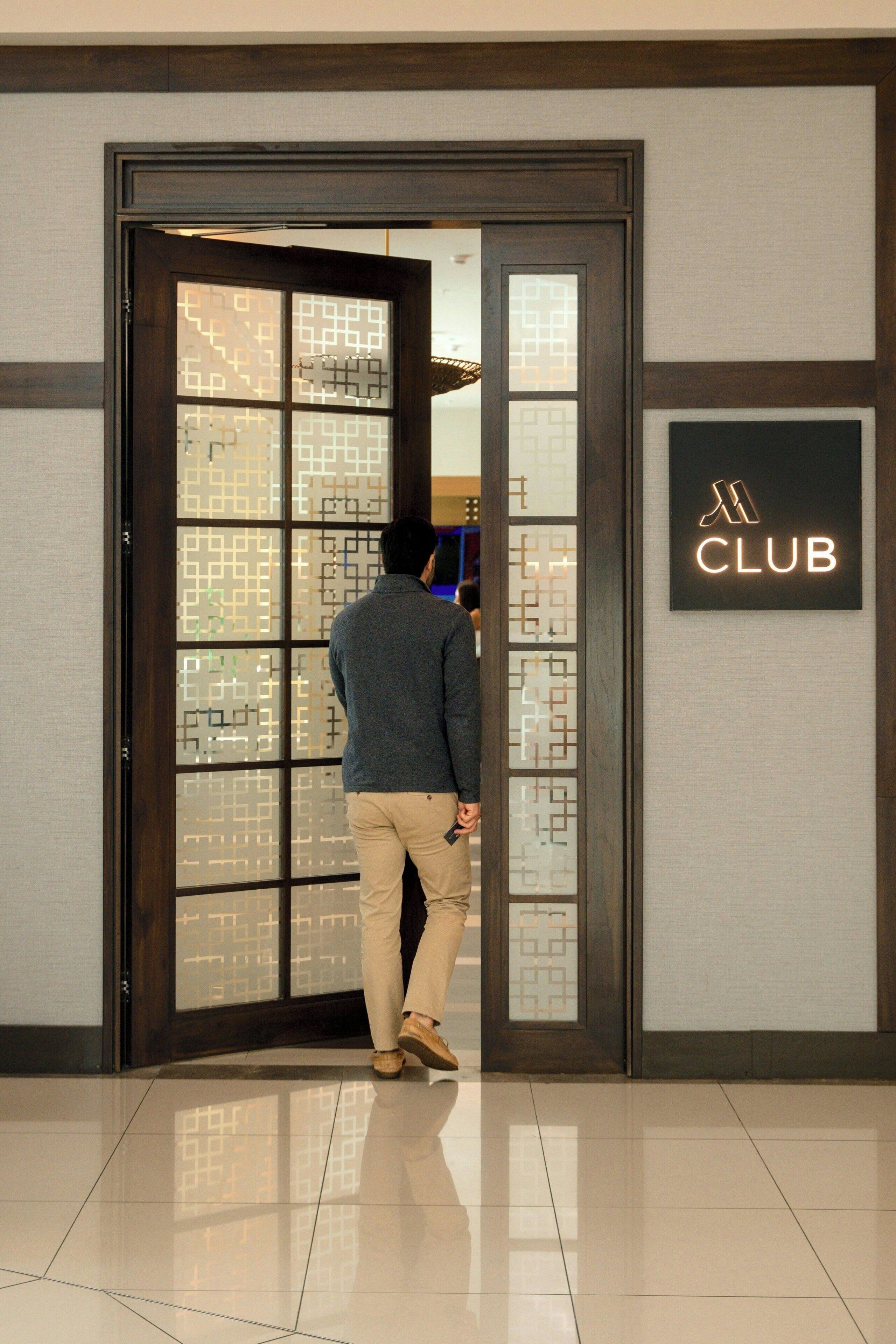 A man in a suit walking through a door with a geometric pattern.