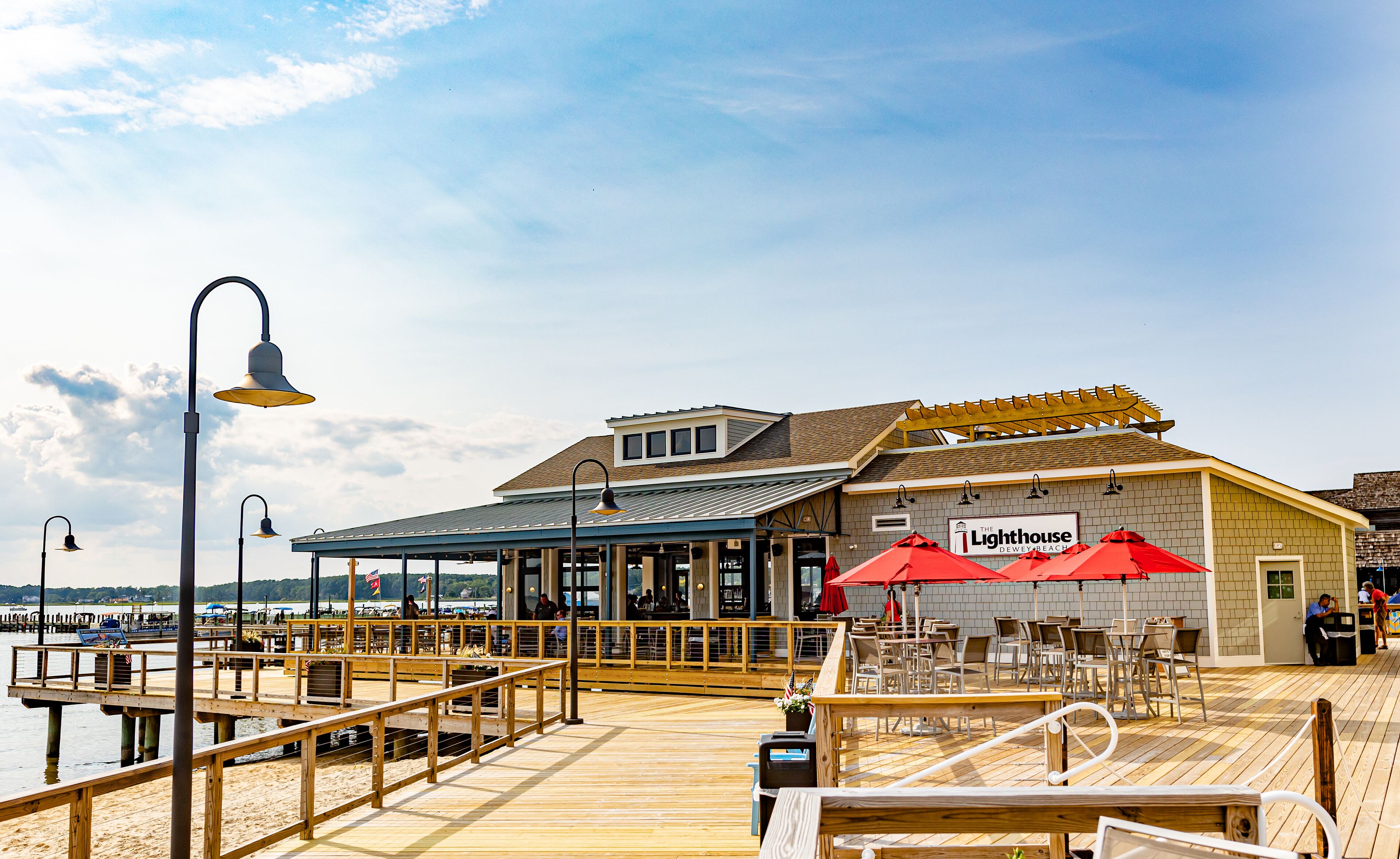 A waterfront restaurant with outdoor seating and a wooden deck.
