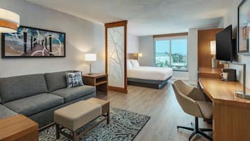 Una habitación de hotel con sofá, cama, escritorio y televisión.