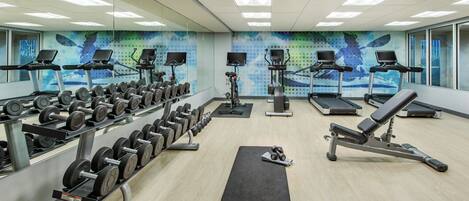 Un gimnasio con cintas de correr, mancuernas y equipamiento de ejercicio.