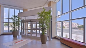 A spacious lobby with large windows, a reception desk, and two potted plants. - Hyatt Place Dewey Beach (Dewey Beach)