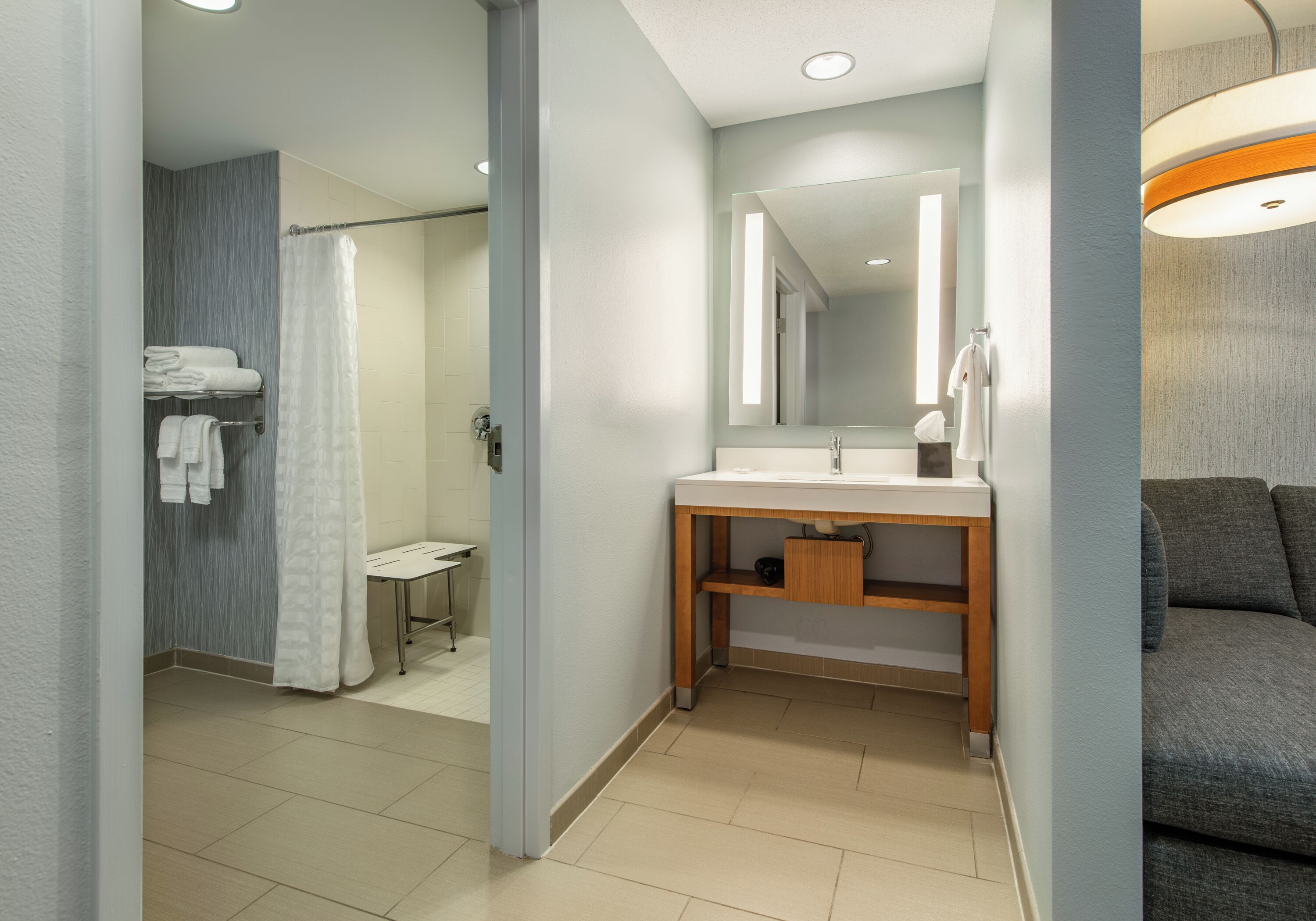 Un bagno moderno con doccia, lavabo con specchio e porta asciugamani.