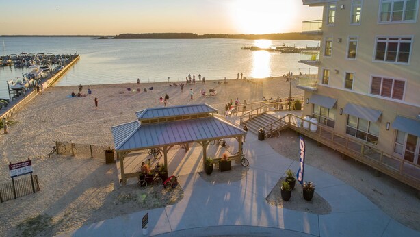 A beachside area with a covered pavilion, a pier with boats, and a building with balconies overlooking the water. - Hyatt Place Dewey Beach (Dewey Beach)