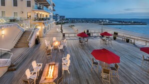A wooden deck with outdoor seating, a fire pit, and a view of the beach and ocean. - Hyatt Place Dewey Beach (Dewey Beach)