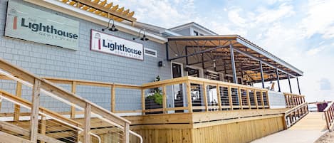 A wooden deck with a railing leading to a covered seating area at the Lighthouse.
