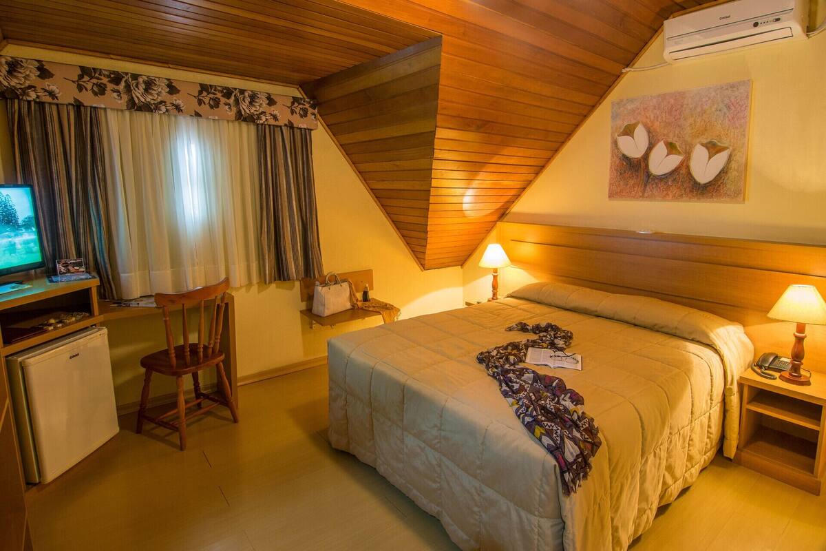 A cozy room with a bed, two bedside lamps, a desk with a computer, and a chair.