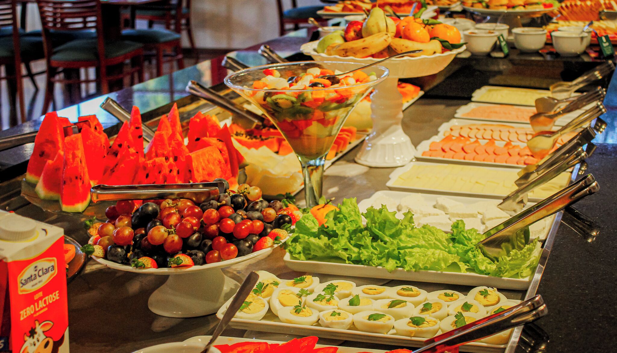 A buffet with various food items including watermelon, grapes, salad, and eggs.