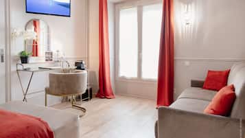 Un salon moderne avec un canapé, une table basse, un téléviseur et une fenêtre avec des rideaux.