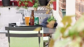 A patio with outdoor seating, a table with drinks, and potted plants.