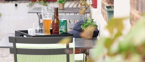 A patio with outdoor seating, a table with drinks, and potted plants.