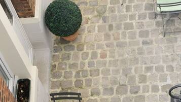 A courtyard with stone flooring, outdoor seating, and a potted plant.