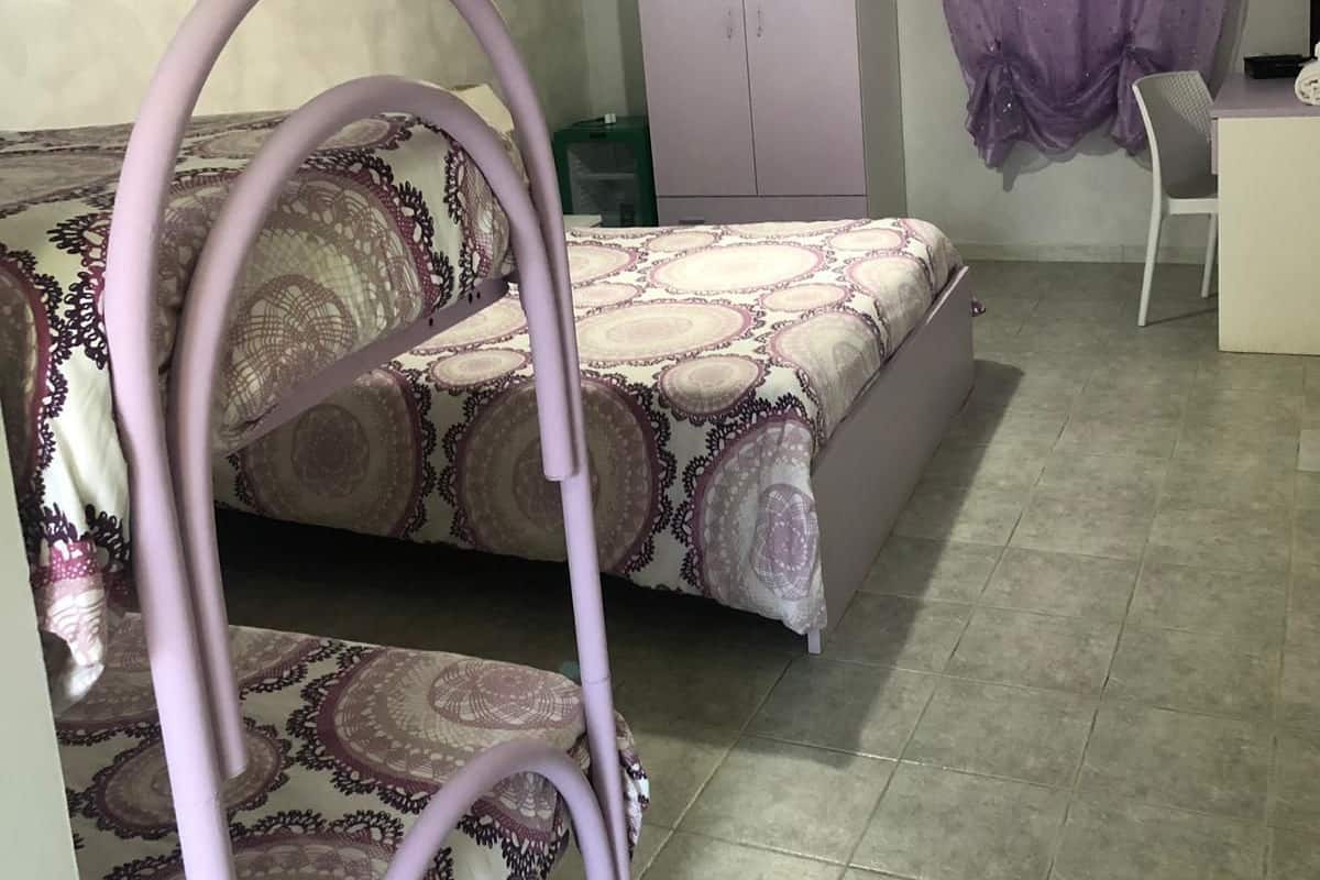 A bedroom with a bed, a chair, a wardrobe, and a desk.
