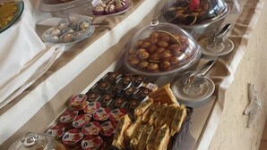 A buffet with various food items, including pastries, fruits, and nuts, displayed in clear containers.