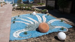 A landscaped garden with a pathway, decorative blue and white tiles, and a large terracotta pot.