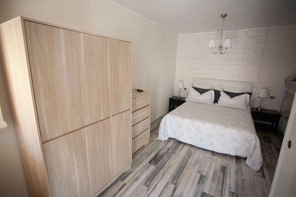 Un dormitorio con cama, mesitas de noche, armario y candelabro.