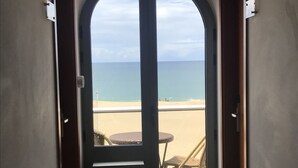 A hallway leading to a beach view with a door, a small table, and a chair.