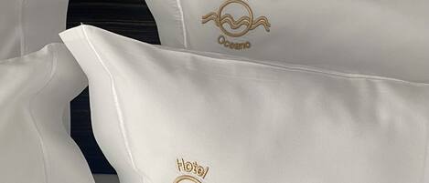 Pillows with embroidered logos of a hotel and ocean waves.
