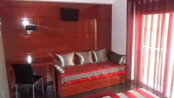 Un dormitorio con cama, escritorio, silla y televisor instalado en la pared.