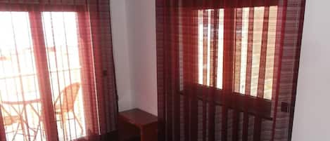 Una habitación con una cama, una mesita y una silla. Se observa un equipo de aire acondicionado en la pared.