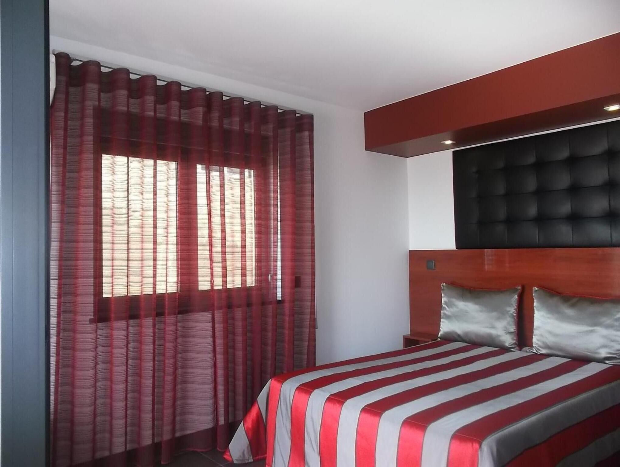 Una habitación de hotel con cama, cortinas y cabecera.