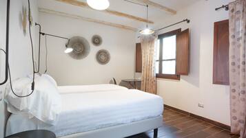 A bedroom with a bed, bedside table, lamp, wall decor, window, and curtains.